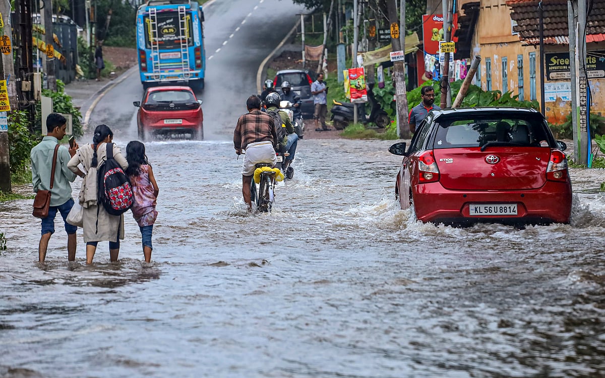 PTI : Commuters make their way through a flooded road following rains, in Kozhikode, Tuesday, July 16, 2024
